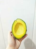 woman holding a slice of fresh ripe avocado photo