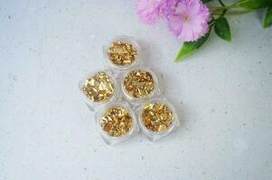 Top view of gold nuggets in glass on white marble background. photo