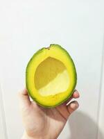 woman holding a slice of fresh ripe avocado photo