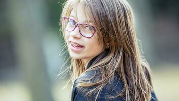 retrato de un contento sonriente Adolescente niña con dental tirantes y lentes foto