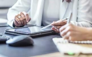 The hands of two female colleagues are using a digital tablet and a notebook. A business meeting to discuss financial management, accounting or financial advice. photo