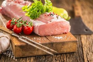 Pork loin fillet parsley herb tomatoes pepper garlic salt and spices on wooden kitchen board. photo