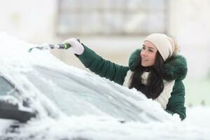 Clearing snow from the car is just one part for good visibility in winter that should be followed by scraping ice from windshields photo