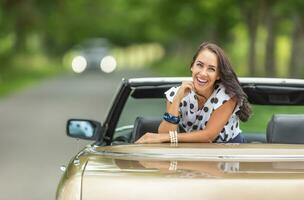 Beautiful girl laughing into a camera turned backwards on a seat of a cabriolet photo