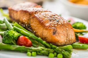 asado salmón filete con espárragos brócoli Zanahoria Tomates rábano verde frijoles y guisantes. pescado comida con Fresco vegetal foto