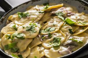 Pasta ravioli stuffed with spinach mustooms prosciutto basil and parmesan cheese photo