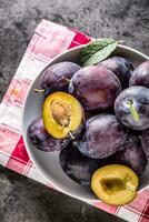 Plums. Fresh juicy plums in a bowl on a wooden or concrete board photo