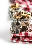 Dried mushrooms in a glass jar on a red checkered tablecloth photo