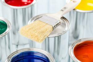 Close-up brush lying on multicolored paint cans. photo