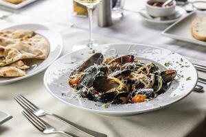 linguini pasta con mejillones y rallado pecorino queso en parte superior servido en un restaurante foto