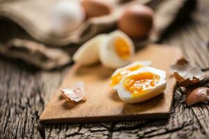 Close-up boiled or raw chicken eggs on wooden board photo