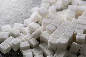 blanco azúcar cubitos rociado en el cocina mesa foto
