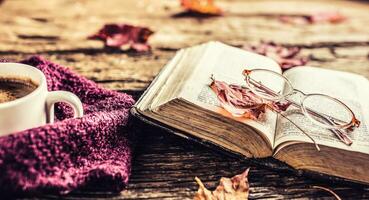 Cup of coffee old  book glasses and autumn leaves. photo