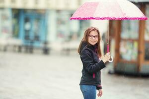 Portrait of happy beautiful young pre-teen girl with pink umbrella under rain. photo