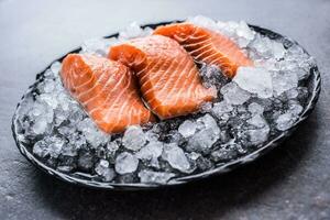 Portioned raw salmon fillets in ice on plate - Close-up. photo