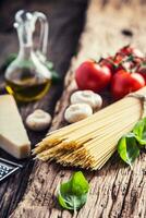 Spaghetti.Spaghetti tomatoes basil olive oil parmesan cheese and mushrooms on very old oak board. Mediterrannean cuisine and ingredients photo