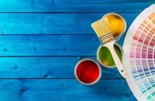 Paint cans color palette, cans opened with brushes on blue table photo