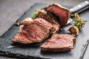 Juicy beef steak with spices and herbs on wooden cutting board photo