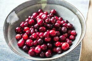 Fresh ripe cranberries in bowl on table close-up photo