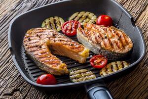 Salmon. Grilled fish salmon. Grilled  salmon steak in grill pan on rustic wooden table photo