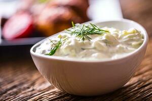 Tzatziki. Tzatziki sauce dip or dressing with chicken grill legs in the background. photo