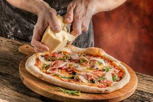 Pizza and Chef. Chef in the restaurant prepares a pizza and decorates it with parmesan cheese photo