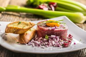 Beef tartare with egg yolk red onion chili peppers herbs and bruschetta photo