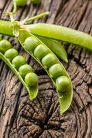 guisantes. Fresco bio hecho en casa chícharos y vainas en antiguo roble tablero. sano Fresco verde vegetal - chícharos y vainas foto