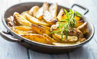 asado patatas en un fritura pan en de madera tablero foto