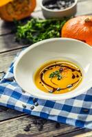 Pumpkin cream soup with seeds and parsley on kitchen table photo