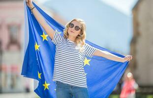 atractivo contento joven niña con el bandera de el europeo Unión foto