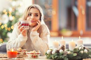 joven hermosa mujer en un Navidad atmósfera participación un taza con café puñetazo o té foto