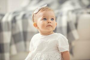 Innocent baby girl looking up with her blue eyes sitting on a floor at home photo