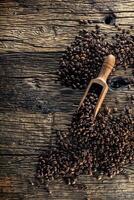 Wooden scoop full of coffee beans on old oak table photo