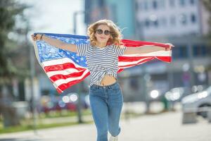 atractivo contento joven niña con el bandera de el unido estados de America foto