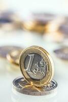 Euro coin balances on another coin and several loose coins photo