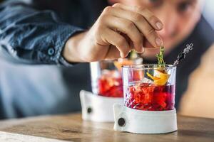 Bartender precisely preparing  cocktail drink with fruit and herb decoration. Bartender only hands preparing alcoholic non-alcoholic drink photo