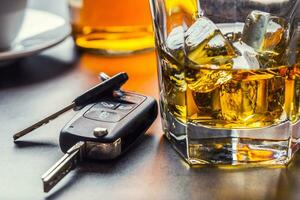 Car keys and glass of alcohol on table. photo