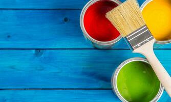 Paint cans color palette, cans opened with brushes on blue table photo