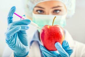 un biólogo mujer genéticamente modifica un manzana para más extenso vida. hembra investigador o científico utilizando laboratorio equipo para jeringuilla y aguja en estéril ropa inyecta el vacuna dentro el comida foto