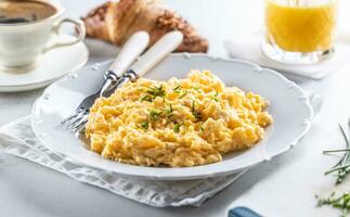 Hotel restaurant serving scrambled eggs with chives next to pastry and beverages photo