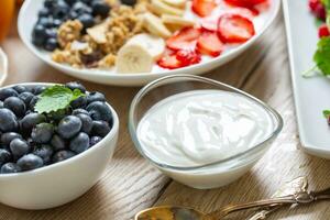 yogur en un vaso cuenco con sano desayuno en mesa foto