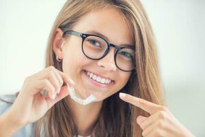 Dental invisible braces or silicone trainer in the hands of a young smiling girl. Orthodontic concept - Invisalign photo