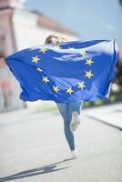 atractivo contento joven niña con el bandera de el europeo Unión foto