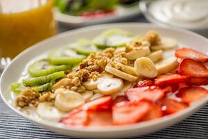 Healthy breakfast served with plate of yogurt muesli kiwi strawberries and banana photo