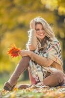 Attractive young woman with sensual smile sitting in autumn park photo