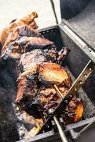 Bbq pork meat juicy and partially charred on a rotating grill outdoors photo