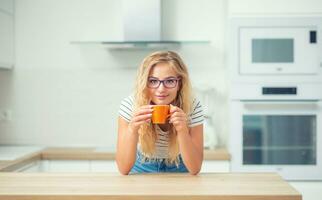 taza de café en mano de contento joven mujer. atractivo niña Bebiendo Mañana té foto