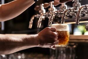 Woman hands of the pub employee tapping beer into a rounded mug. photo