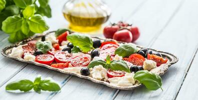 caprese ensalada con queso Mozzarella queso maduro Tomates aceitunas y albahaca hojas. italiano o Mediterráneo sano comida foto